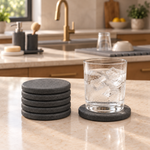 A stack of Trivelle stone coasters beside a glass of iced water resting on one
