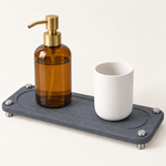Dark Gray — Dark gray stone sink caddy holding an amber soap bottle and a stone cup