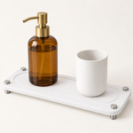 White — White stone sink caddy holding an amber soap bottle and a stone cup