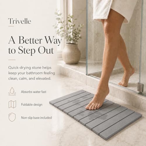 Stepping out of a glass shower onto the gray diatomite stone bath mat