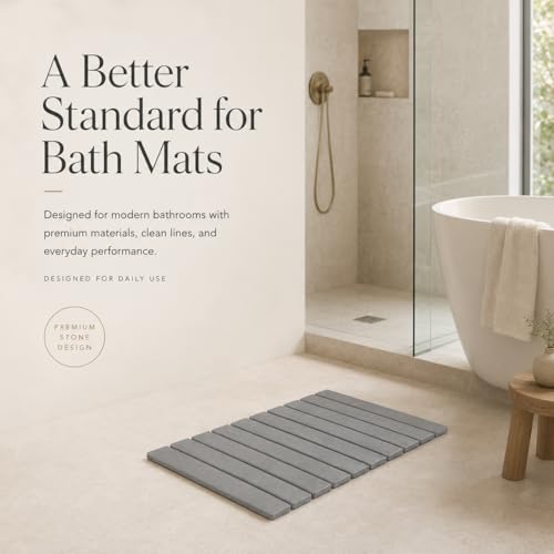 Gray stone bath mat in a modern bathroom beside a freestanding tub and walk-in shower