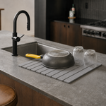 Trivelle stone drying mat beside a kitchen sink with an upside-down pan and two fluted glasses air-drying