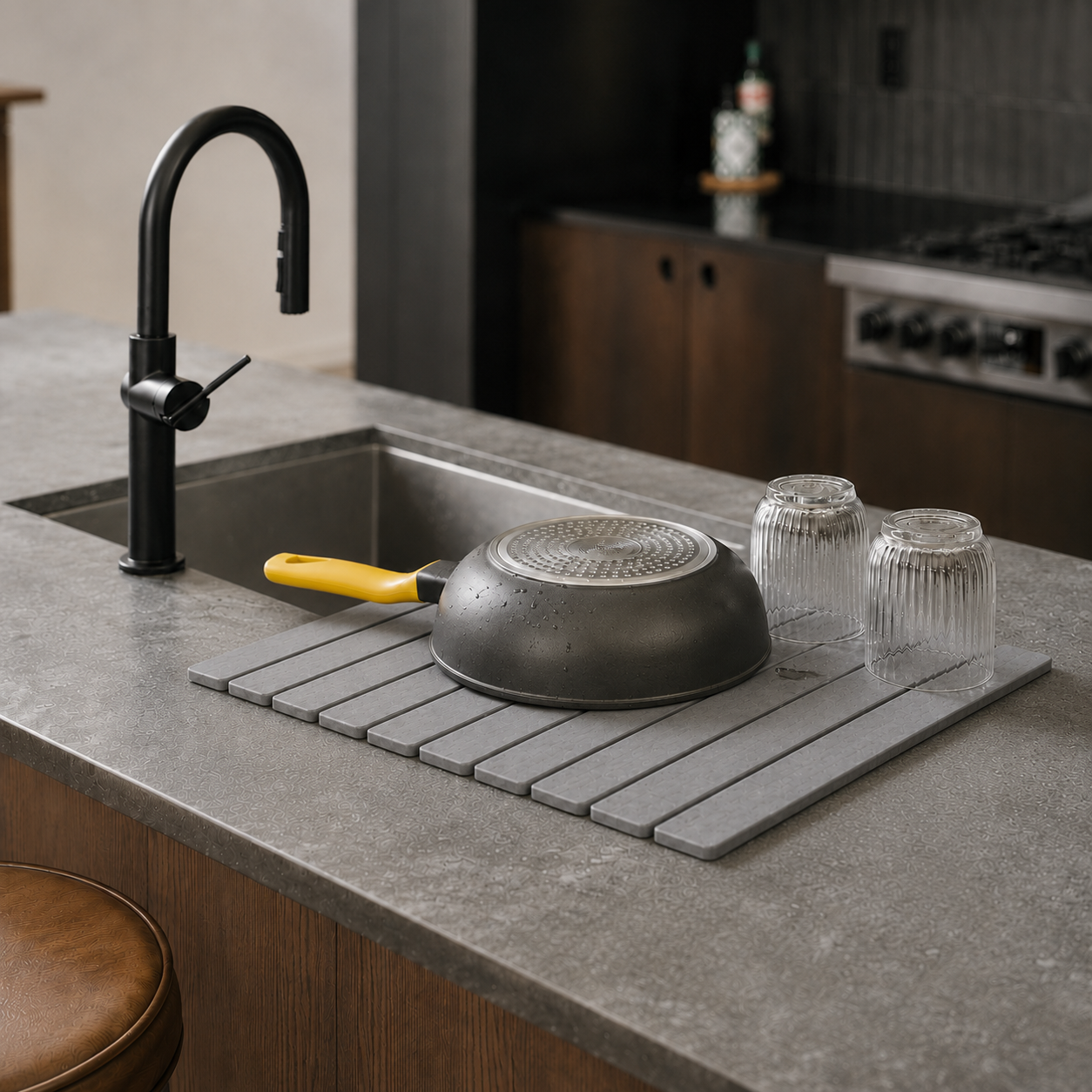 Trivelle stone drying mat beside a kitchen sink with an upside-down pan and two fluted glasses air-drying