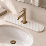 White — White stone faucet mat on a bathroom vanity behind a brass tap