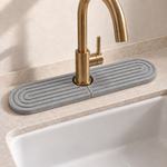 Dark Gray — Dark gray stone faucet mat catching splashes behind a kitchen faucet