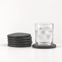 Stone Coaster Set, six stacked dark gray coasters beside a cold glass