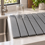 Close-up of the stone drying mat slats with an upturned glass drying by the sink. Glass shown for styling, not included