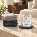 Stacked stone coasters from the Essential Kitchen Set beside a cold glass resting on one. Glass shown for styling, not included
